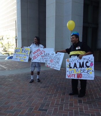 Dael Wilcox holds up signs protesting any rules or regulations for beekeeping in Los Angeles (Jen Nowell/Neon Tommy)