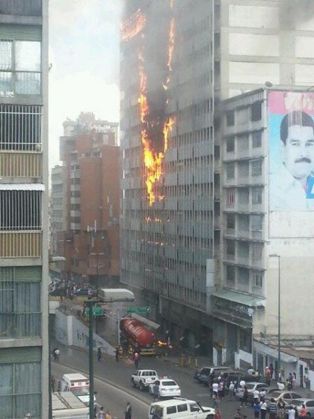 A building in Caracas burns next to a mural of Nicolas Maduro/via Twitter @esosiequetetengo 