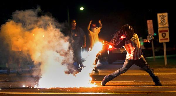 A protestor throws a tear gas canister back at police on Aug. 12. (@kodacohen/Twitter)