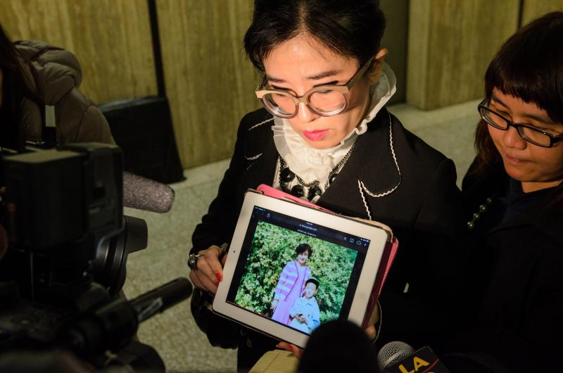 Rose Tsai, attorney for Xinran Ji's family, shows reporters a video of Ji with his family during his childhood in China after a preliminary hearing on 12/12/14 (Benjamin Dunn/Neon Tommy).