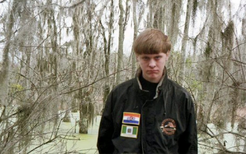 Dylann Storm Roof scowls while wearing a jacket with the flags suggestive of the apartheid-era in South Africa, the other from white-ruled Rhodesia. (Photo via Roof’s Facebook)