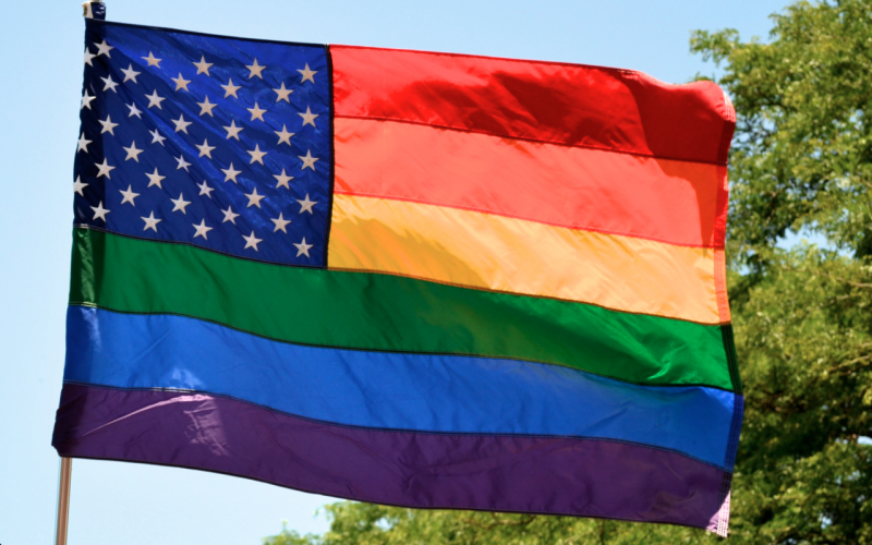 Rainbow American flag waives in wind. (Flickr/nathanmac87)