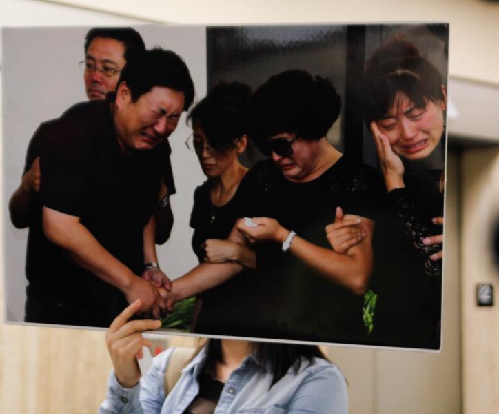 A Chinese supporter holds a photo of Xinran Ji's crying family. (Sophia Li / Neon Tommy)