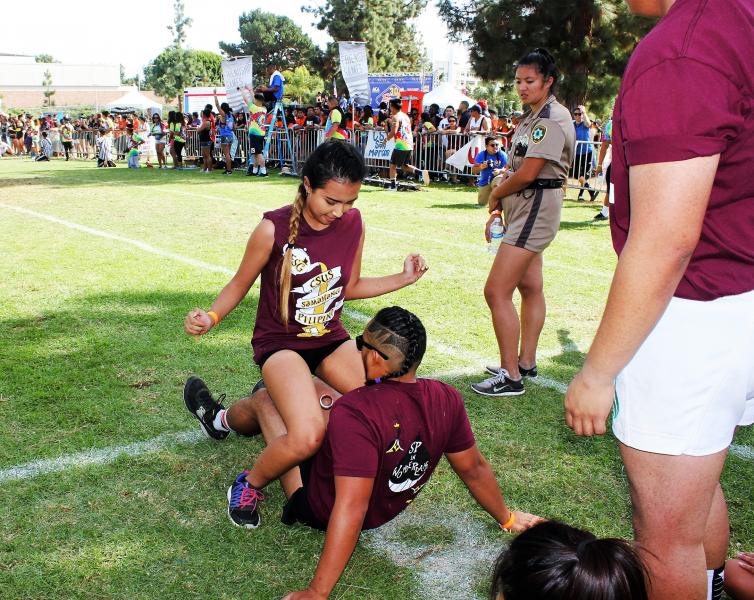 Students from CSUS compete in "The Nasty," in which a person must run across a field with a PVC pipe between his or her legs and transfer the pipe to a teammate without the use of hands. (Heidi Carreon/Neon Tommy)