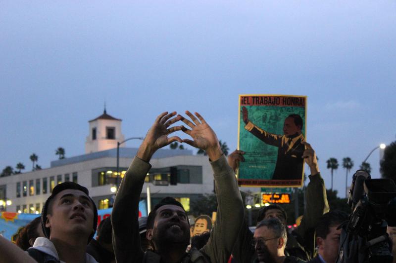 Men signal to people in the Los Angeles Metropolitan Detention Center during the watch party. (Rebecca Gibian/Neon Tommy)