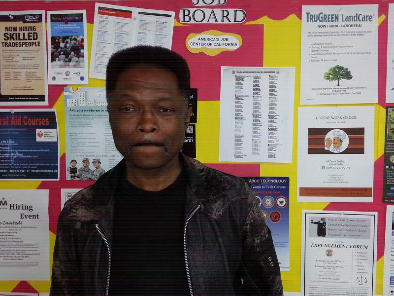 Darryl Walker poses in front of the Job Board at the South L.A. WorkSource Center, Dec. 10, 2014. (Taylor Haney/Neon Tommy)