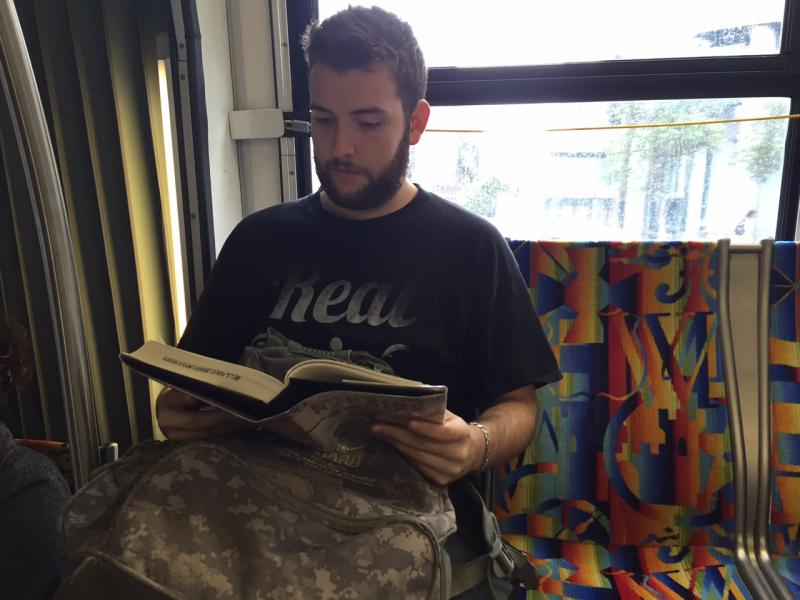 Nick Horton reads a book during his morning commute on the 720 bus (Carla Javier / Annenberg Media)
