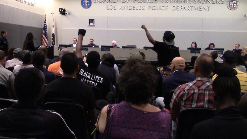 Richards pumps her fist while protesting during a police commission meeting (Helen Zhao / Neon Tommy)