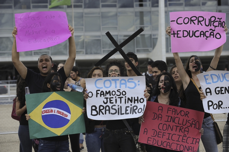 Demonstrators in Brasilia protest the new affirmative action law with signs reading things like "Less corruption, more education." (Agência Brasil)