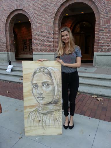 SCALE member Natalie Biehl stands with a picture of Bangladesh worker, Aklima Khanam, who was trapped under rubble for two days (Eric Parra)