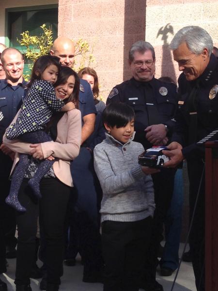 Jaequon Santos, 9, receives a toy police car from South Pasadena Police Chief Art Miller. Jaequon was honored Thursday for calling 911 and saving his younger sister from choking to death. (Melissah Yang/Neon Tommy)