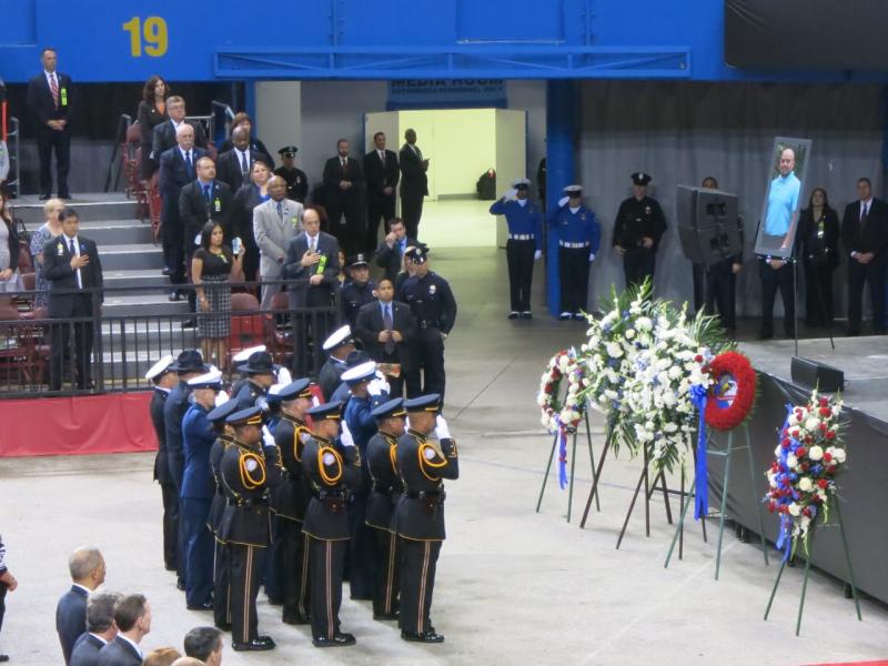 Officers salute a photo of killed TSA agent Gerardo Hernandez. (Taiu Kunimoto/Neon Tommy)