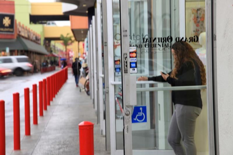 A Fashion District shop owner kills time in front of her empty store. (Meng Meng/Neon Tommy)